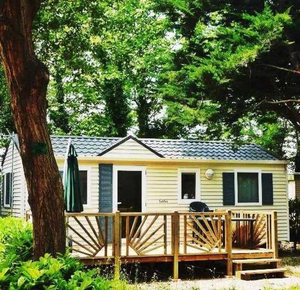 une petite maison jaune avec une terrasse couverte en bois dans l'établissement Camping 4 étoiles - Parc aquatique - efaaa0, à Canet