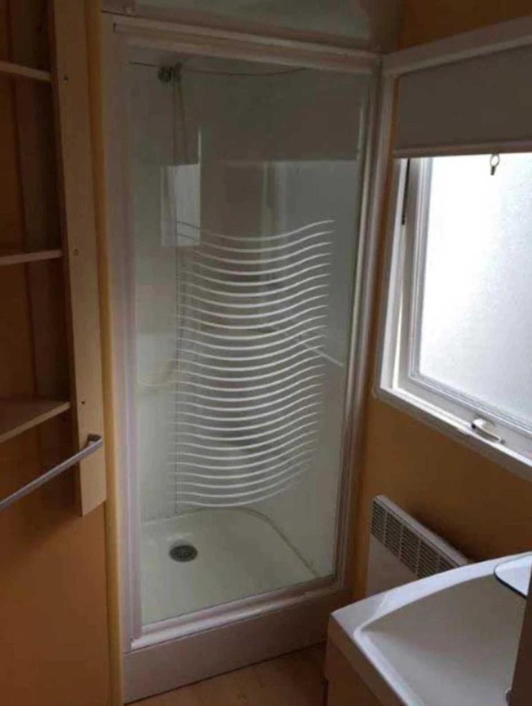une douche en verre dans une salle de bain avec un lavabo dans l'établissement Camping 4 étoiles - Piscine - ccaaagh, à Carennac 37 autres photos