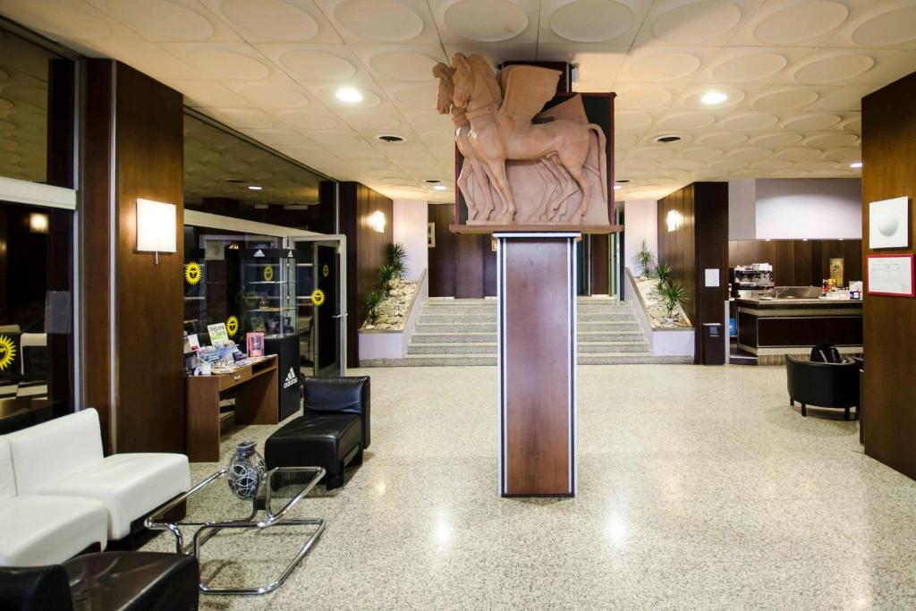 un hall avec une statue d'une femme sur une colonne dans l'établissement Grand Hotel Helios, à Tarquinia 80 autres photos