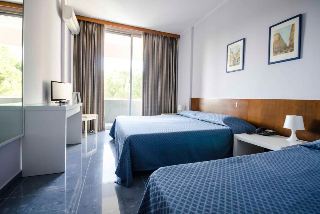 une chambre d'hôtel avec deux lits et une télévision dans l'établissement Grand Hotel Helios, à Tarquinia