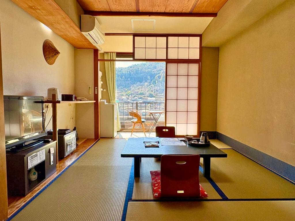 un salon avec une table et une grande fenêtre dans l'établissement Yunominesou, à Hongu