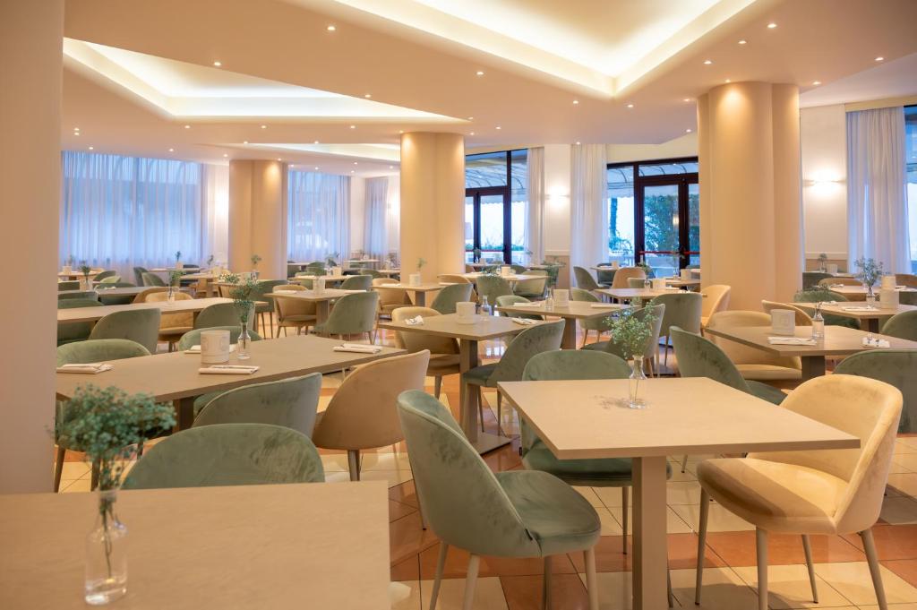 un restaurant avec des tables, des chaises et des fenêtres dans l'établissement Hotel Savoy, à Caorle