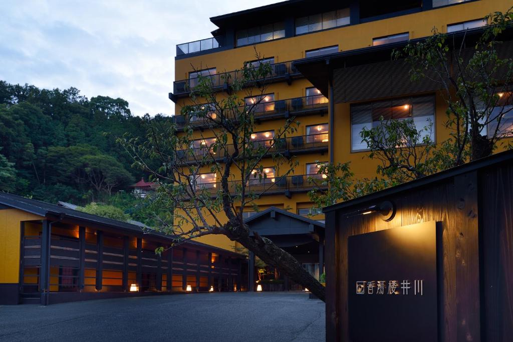 un grand bâtiment jaune avec un arbre devant lui dans l'établissement Kouyurou Ikawa, à Izunokuni