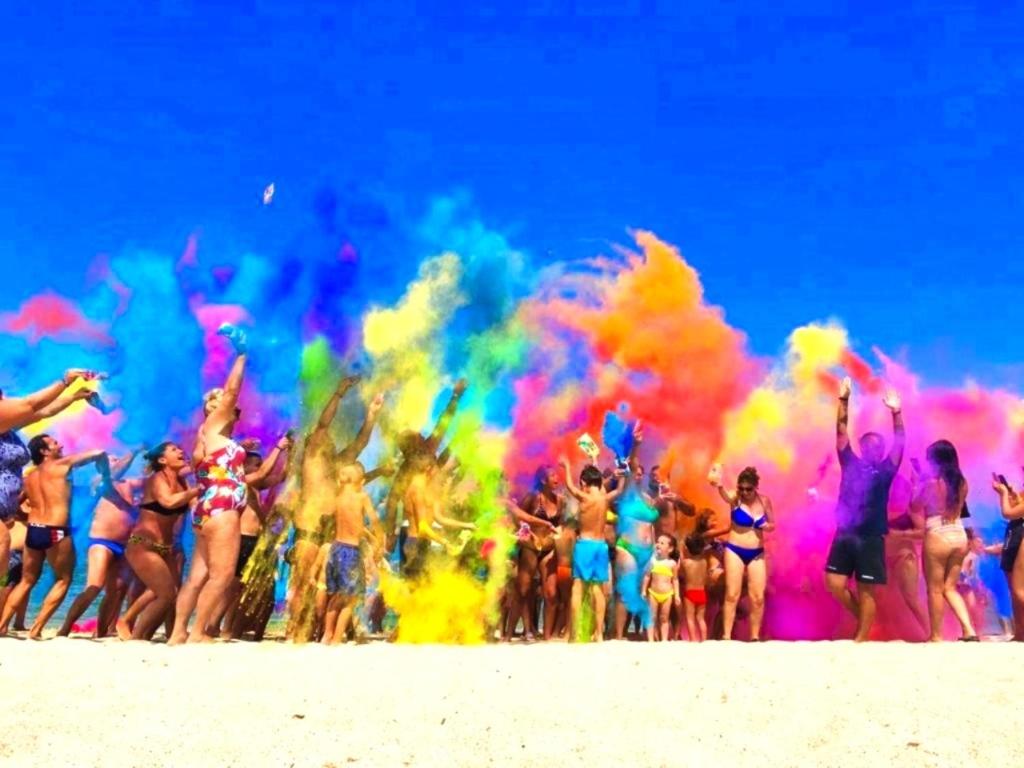 un groupe de personnes jouant avec des couleurs sur la plage dans l'établissement La Porta del Sole Hotel & Village, à San Ferdinando