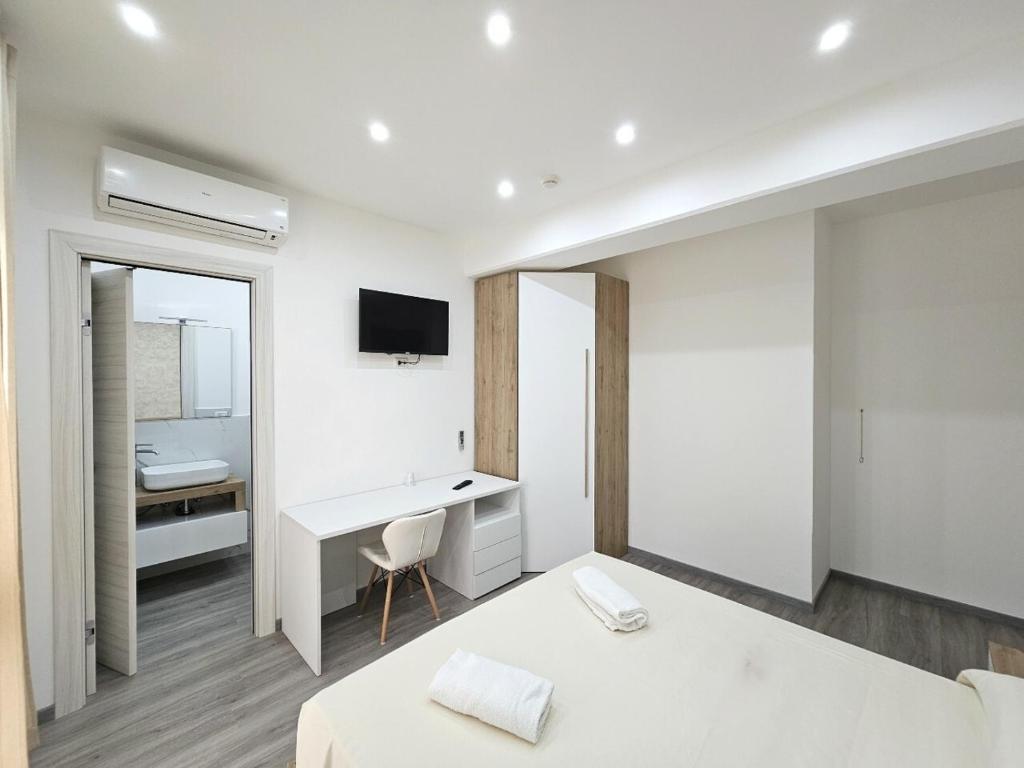 - une chambre blanche avec un bureau et un lit dans l'établissement Hotel Baia del Cigno, à Torre San Giovanni