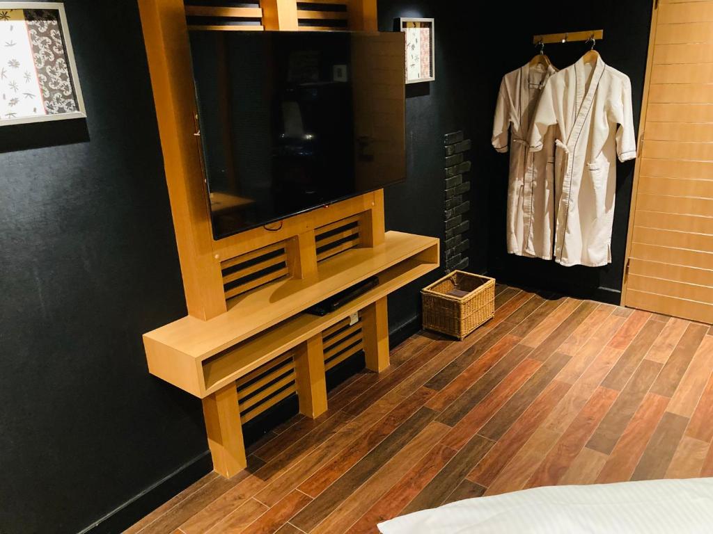 une chambre avec une télévision et une commode avec une commode dans l'établissement ホテル パレドフルー, à Toyonaka