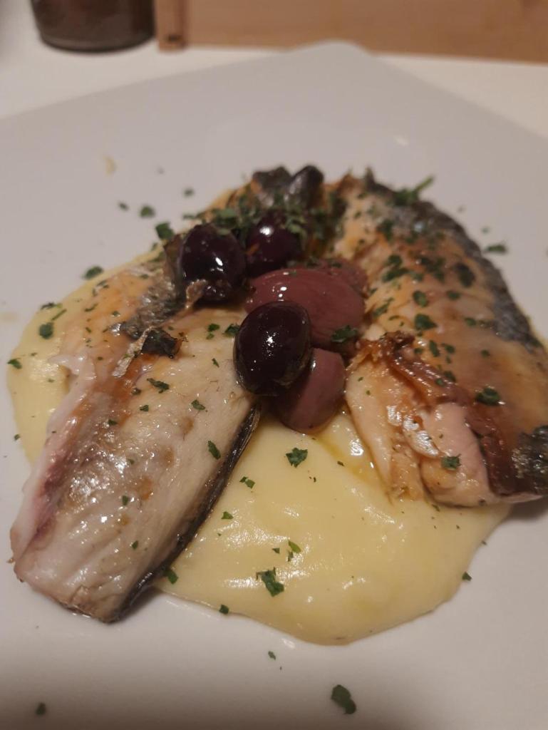 un morceau de viande avec du raisin et du fromage sur une plaque dans l'établissement Residence Parco del Sole, à Rodi Garganico