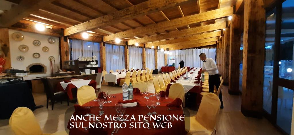 un homme debout dans un restaurant avec des tables et des chaises dans l'établissement Residence Parco del Sole, à Rodi Garganico