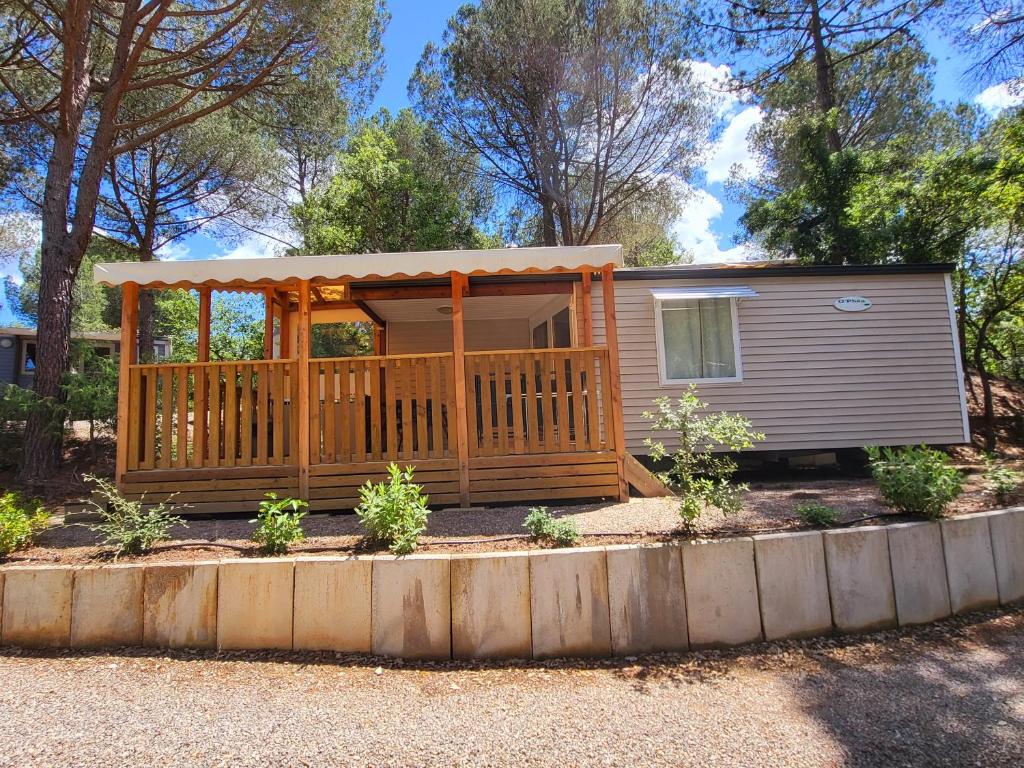 une petite maison avec un porche et une terrasse dans l'établissement Mobilehome Leï Suves Côte d'Azur, à Roquebrune-sur Argens