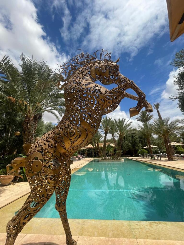 une statue d'une personne debout devant une piscine dans l'établissement Riad le Jasmin, à Taroudant
