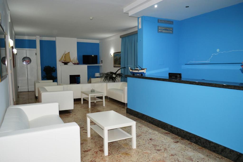 un hall d'entrée avec des meubles blancs et un mur bleu dans l'établissement Delfino, à Marina di Camerota
