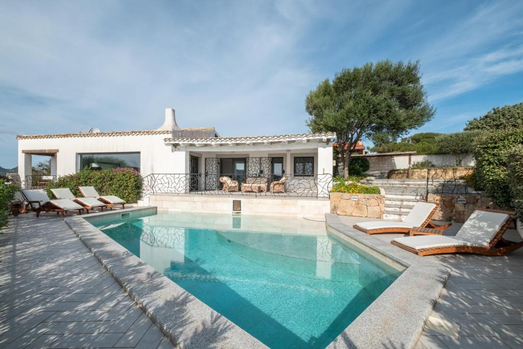 une piscine avec des chaises et une maison dans l'établissement Piscina Privata- Luxury Villa 100m dalla Spiaggia, à Palau
