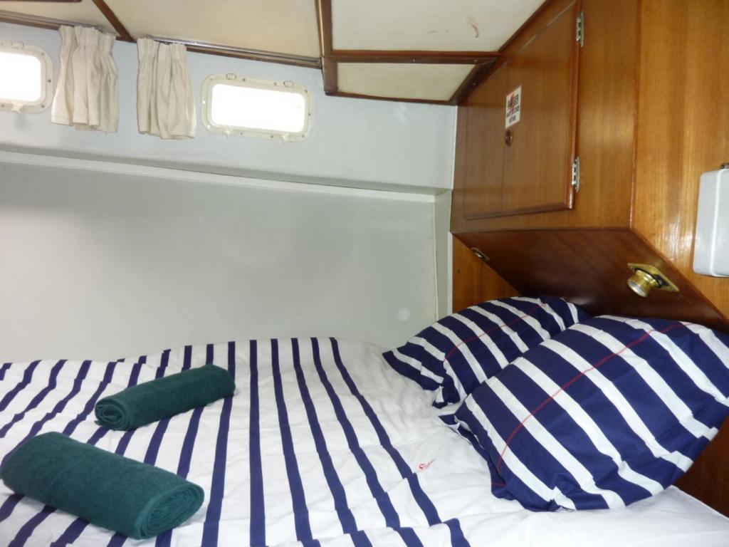 - un lit avec des oreillers rayés bleus et blancs sur un bateau dans l'établissement Bateau PAPAYE, à Sète
