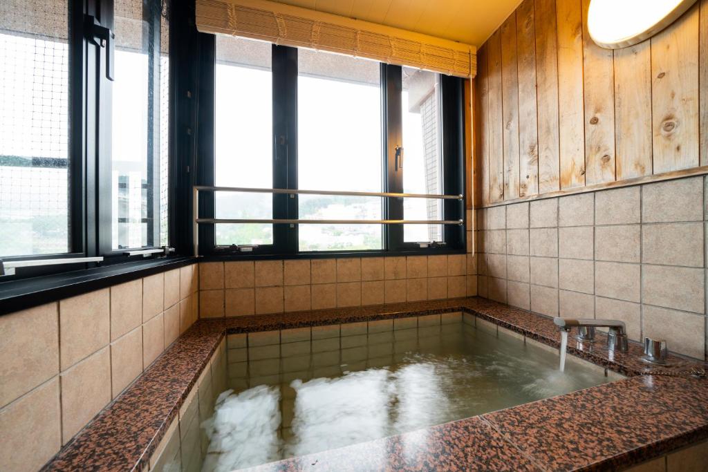 La salle de bains est pourvue d'une baignoire avec de l'eau. dans l'établissement Beppu Kannawa Onsen Oniyama Hotel, à Beppu