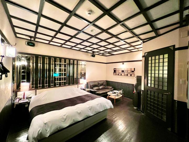 une chambre avec un grand lit et un canapé dans l'établissement SKY JZauruss バズるホテル ,Dinosaur Love Hotel, à Beppu