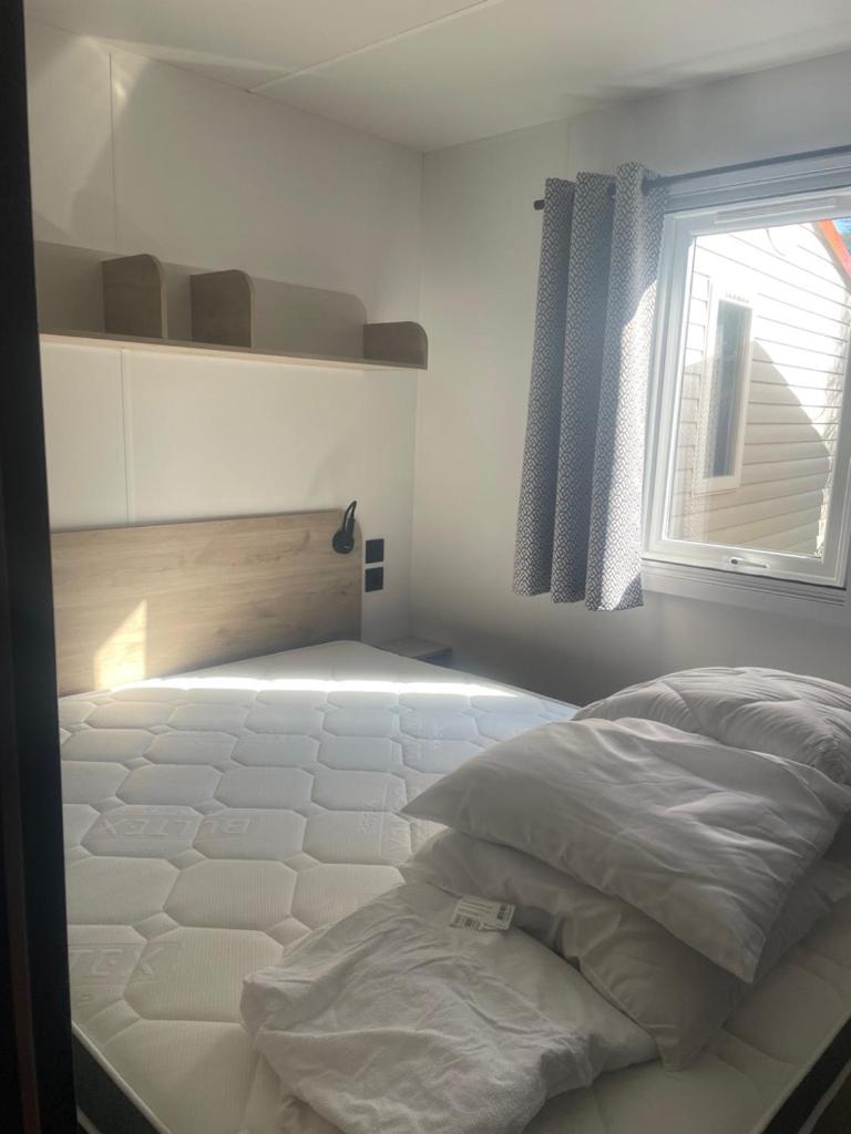 une chambre blanche avec un lit et une fenêtre dans l'établissement Mobil-home neuf 6 à 8 pers au Camping Les Palmiers, Hyères, à Hyères