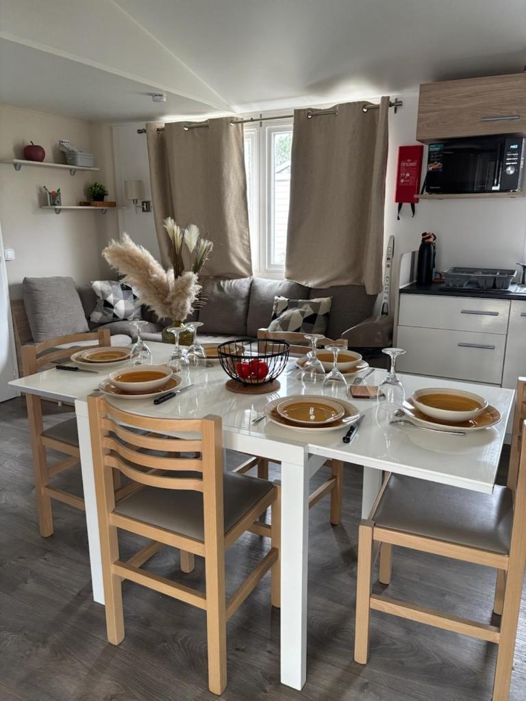 - une table blanche avec des chaises et des assiettes dans la cuisine dans l'établissement Mh 3 ch - 1 sdb - terrasse couverte - kerlann, à Pont-Aven