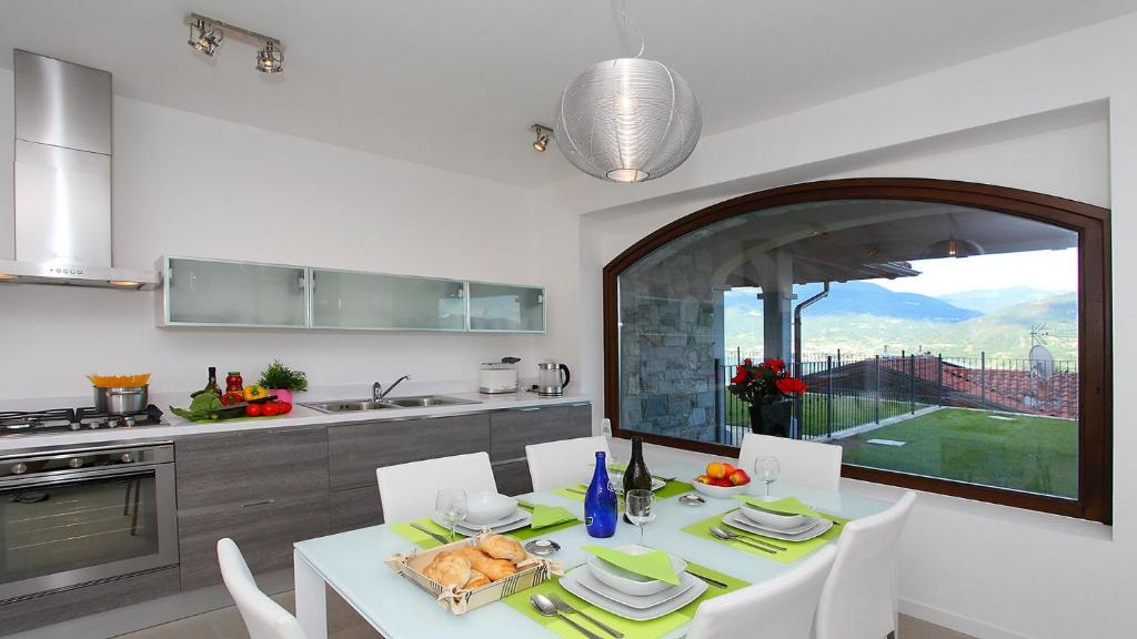 une cuisine avec une table et des chaises ainsi qu'une grande fenêtre dans l'établissement Villa Serena, à Plesio 14 autres photos