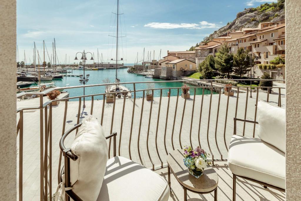d'un balcon avec des chaises et une vue sur le port de plaisance. dans l'établissement Tivoli Portopiccolo Sistiana Wellness Resort & Spa, à Sistiana
