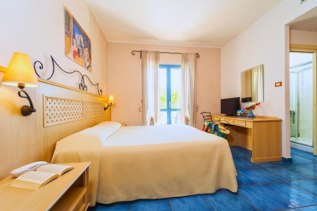 une chambre d'hôtel avec un lit et un bureau dans l'établissement Hotel Ipomea Club, à Capo Vaticano
