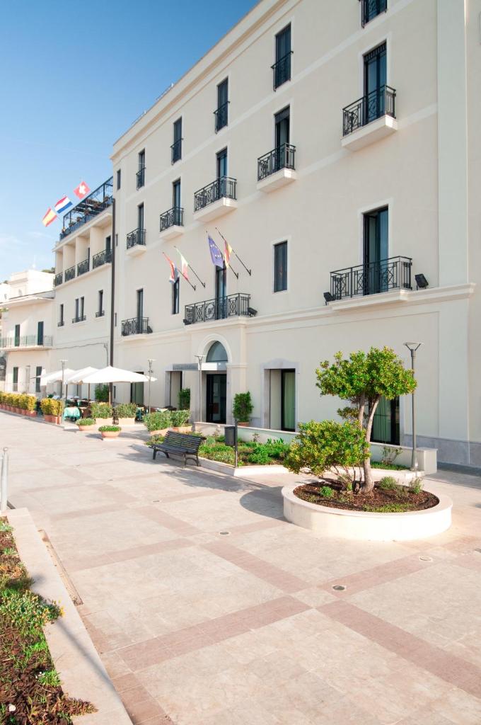 un grand bâtiment blanc avec deux drapeaux américains dans l'établissement Grand Hotel Mediterraneo, à Santa Cesarea Terme