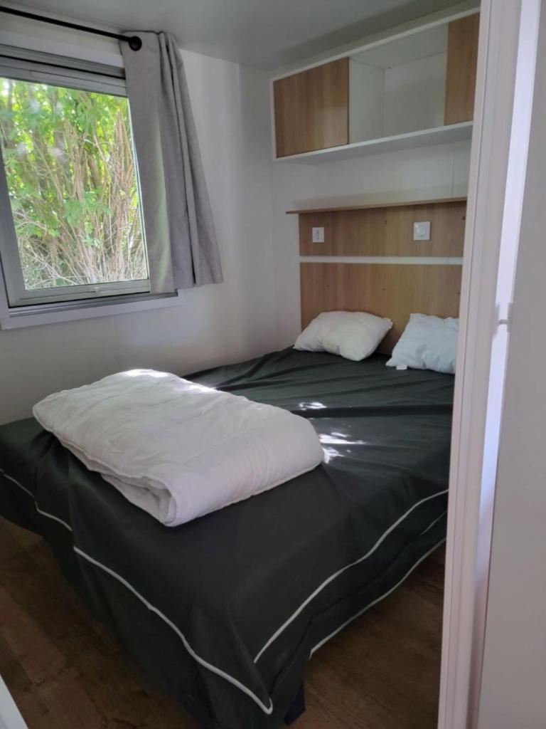 deux lits dans une petite pièce avec une fenêtre dans l'établissement Mobil home Céleste 6-8 personnes, à Litteau