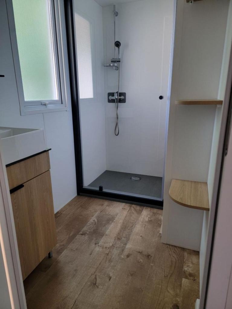 une salle de bain avec une douche avec un lavabo et un miroir dans l'établissement Mobil home Céleste 6-8 personnes, à Litteau