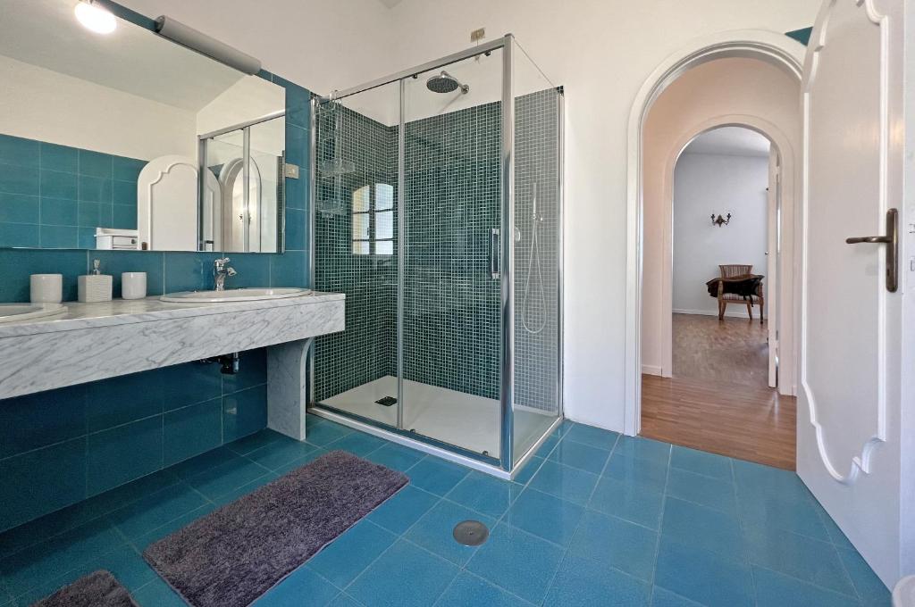 La salle de bains est pourvue d'une douche en verre et de carrelage bleu. dans l'établissement Villa Collina Del Sole 12 Pax by VILLASRETREATS, à Nicola