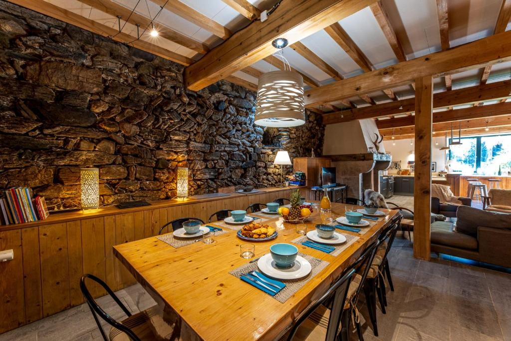 Cette chambre dispose d'une grande table en bois et d'un mur en pierre. dans l'établissement Grand gîte 4 étoiles - Bain nordique, à Aste-Béon