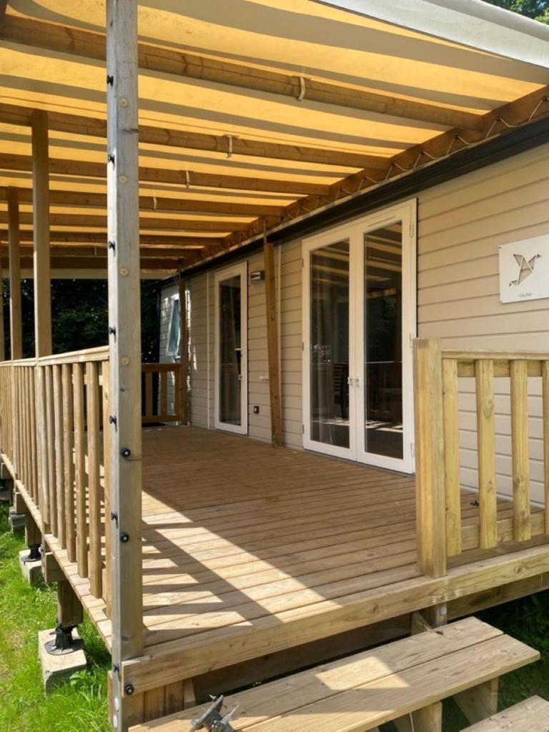 une terrasse en bois avec un auvent sur une maison dans l'établissement Mobil Home Calina 4-6 personnes, à Litteau