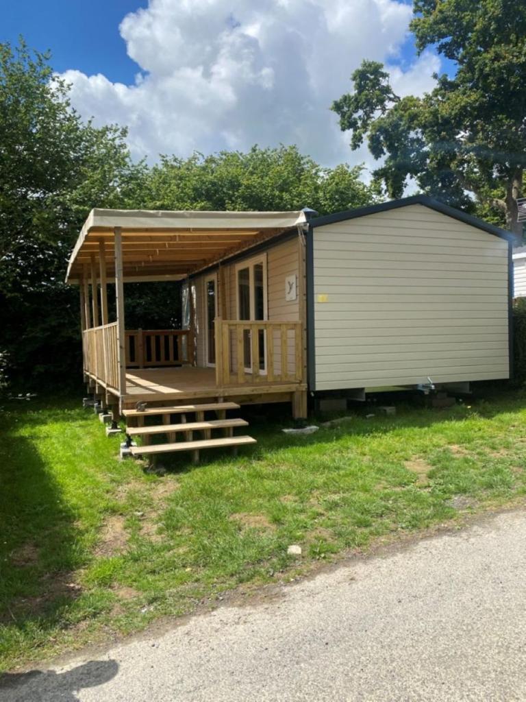 Cette grande cabane en bois dispose d'une terrasse couverte et d'escaliers. dans l'établissement Mobil Home Calina 4-6 personnes, à Litteau
