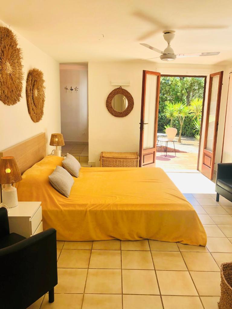 - une chambre avec un grand lit jaune et une terrasse dans l'établissement Villa EnriMar, à Capoliveri