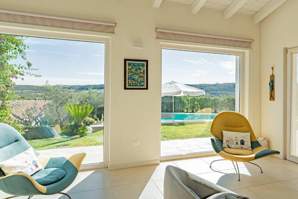 - un salon avec deux chaises et une porte coulissante en verre dans l'établissement Villa dei Gruccioni - YourPlace Abruzzo, à Torino di Sangro