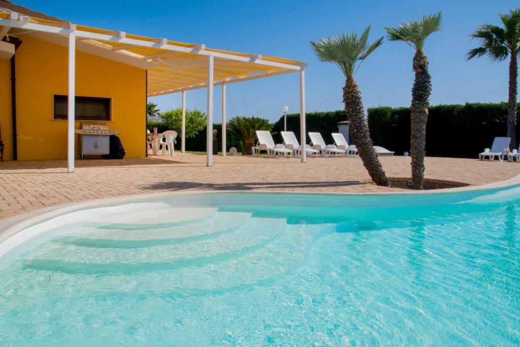 - une piscine bordée de palmiers en face d'une maison dans l'établissement Villa Carrino by MMega, à Racale