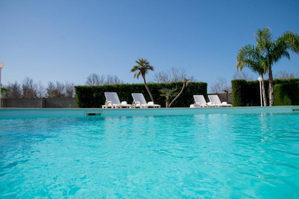 une grande piscine avec chaises et palmiers dans l'établissement Villa Carrino by MMega, à Racale