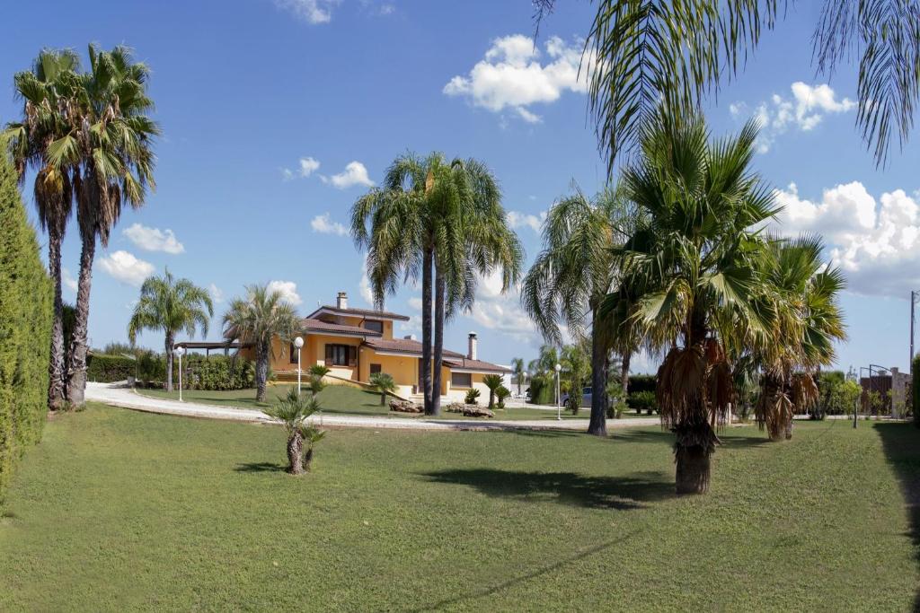 une maison avec des palmiers en face d'une cour dans l'établissement Villa Carrino by MMega, à Racale