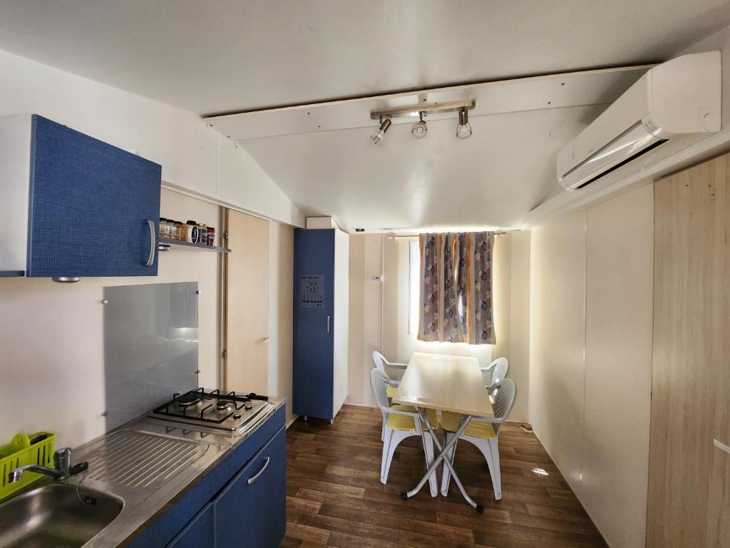 une cuisine avec des armoires bleues et une table et des chaises dans l'établissement Camping poney, à Sainte-Croix-de-Verdon