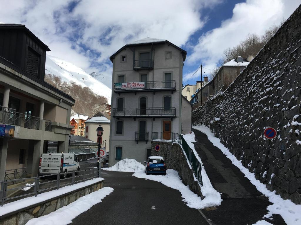 un bâtiment avec une voiture garée dans une rue enneigée dans l'établissement Appartement n° 32, à Barèges