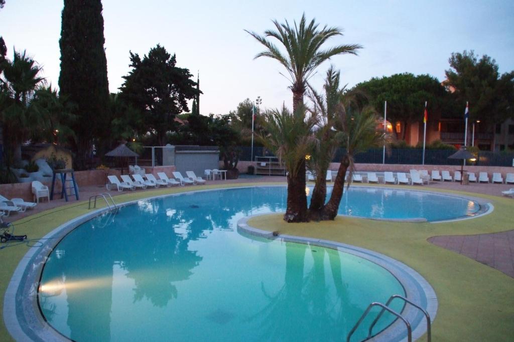 une grande piscine avec palmiers et chaises dans l'établissement Camping de la Baie, à Cavalaire-sur-Mer