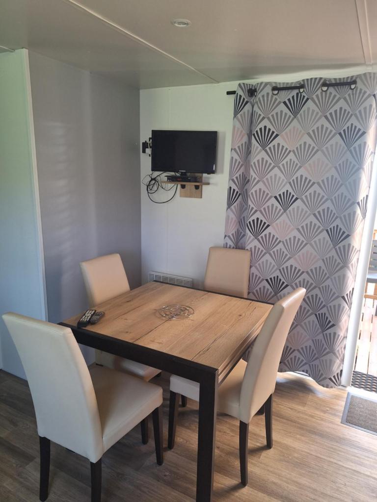 une table à manger avec des chaises blanches et une télévision dans l'établissement MH 535 Tout équipé 3 CHAMBRES 1 SDB dans camping 4 étoiles, à Saint-Julien-en-Born