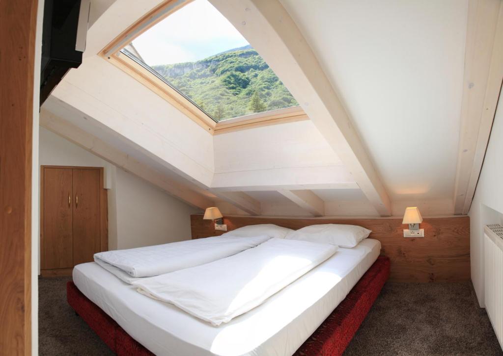 une chambre avec un grand lit avec une lucarne dans l'établissement Überbacherhof, à Termeno