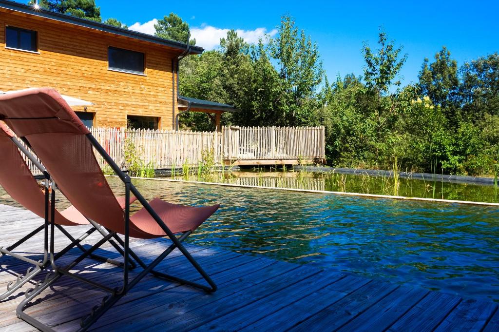 une paire de chaises assises sur une terrasse à côté d'une piscine dans l'établissement Bivouac nature, Tentes Lodges dans les Cévennes, à Saint-Jean-du-Gard
