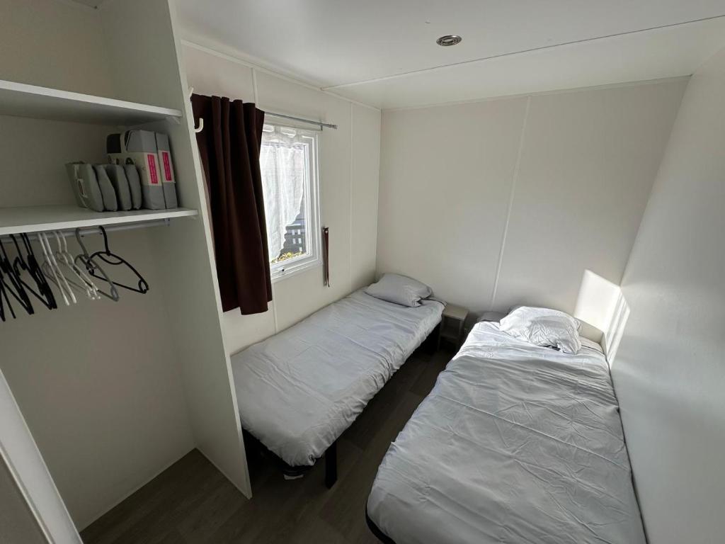 une petite chambre avec deux lits et une fenêtre dans l'établissement Bungalow 4-6 personnes, à Lattes