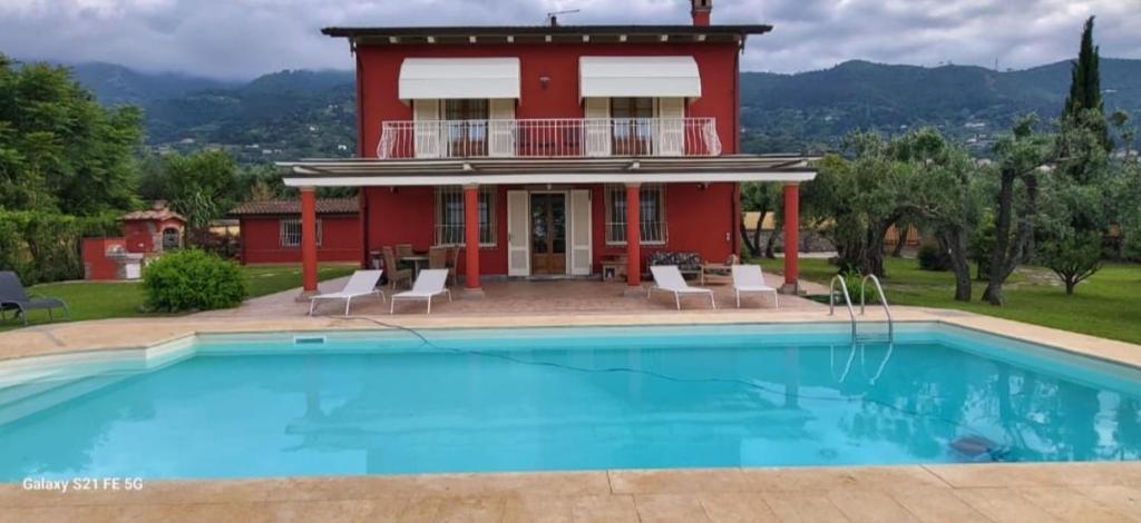 une maison avec une piscine en face d'une maison rouge dans l'établissement Villa Bice in Versilia, à Pietrasanta