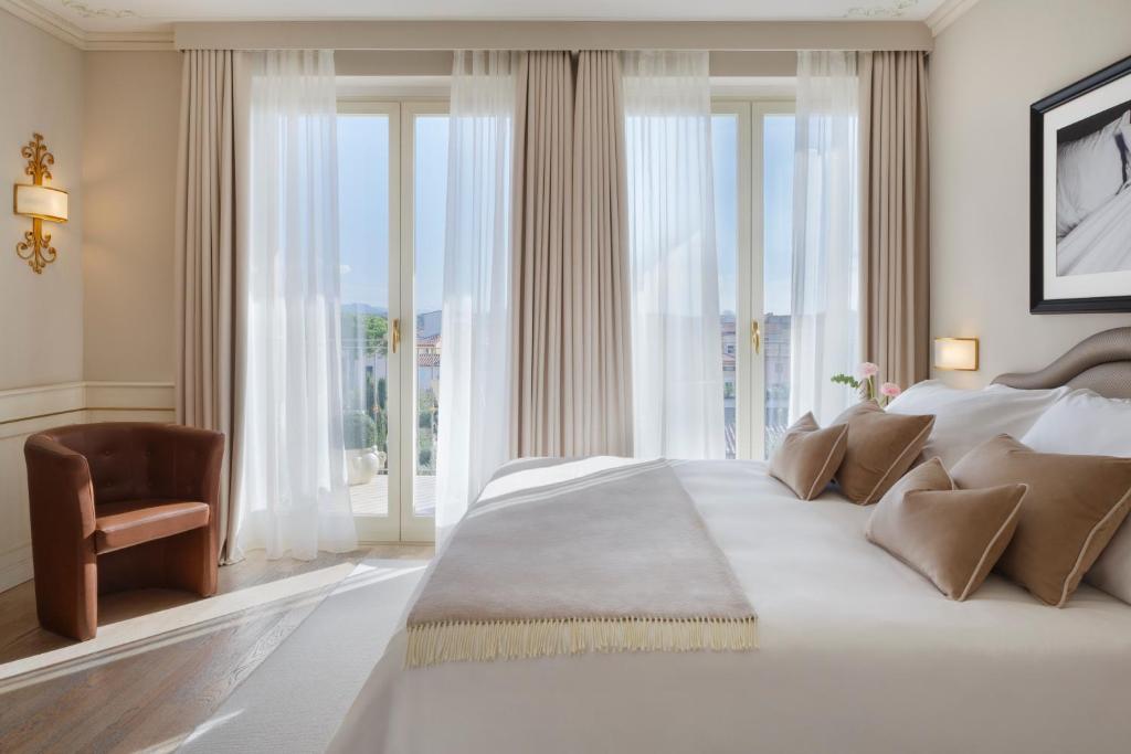 une chambre avec un grand lit et de grandes fenêtres dans l'établissement Grand Hotel Imperiale, à Forte dei Marmi