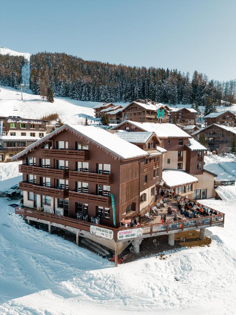 un grand bâtiment avec de la neige au sol dans l'établissement Hotel Emeraude, à Peisey-Nancroix