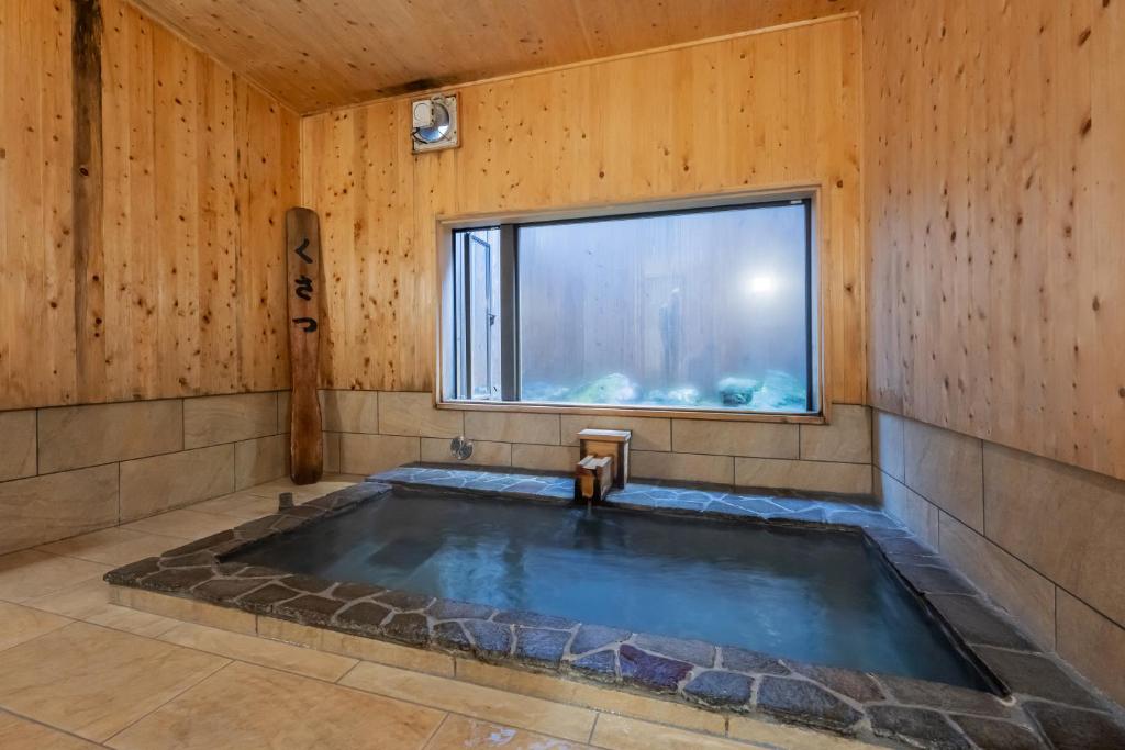 - un bain à remous dans une chambre avec fenêtre dans l'établissement うり房旅館仲通り うら房, à Kusatsu