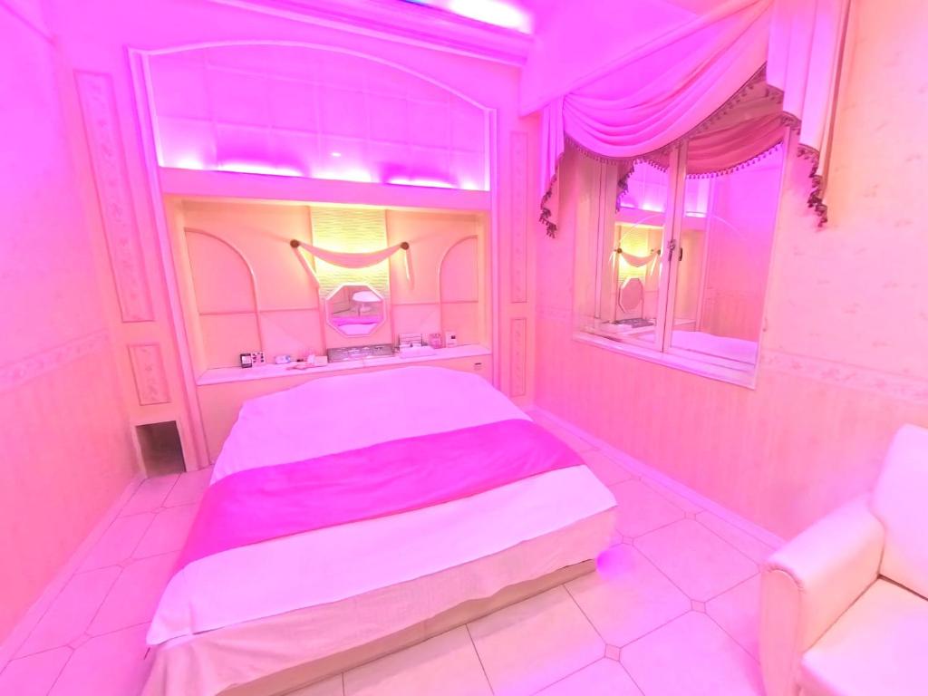 - une chambre rose avec un lit et une fenêtre dans l'établissement ホテル ニューパレス, à Amagasaki