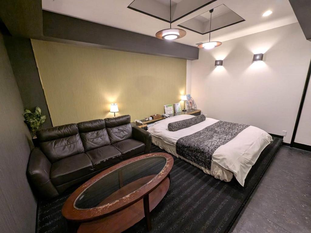 une chambre d'hôtel avec un lit et un canapé dans l'établissement Hotel First (Adult Only), à Ikeda