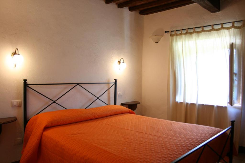 - une chambre avec un lit doté d'une couette en orange et d'une fenêtre dans l'établissement Borgo Antico, à Poggioni